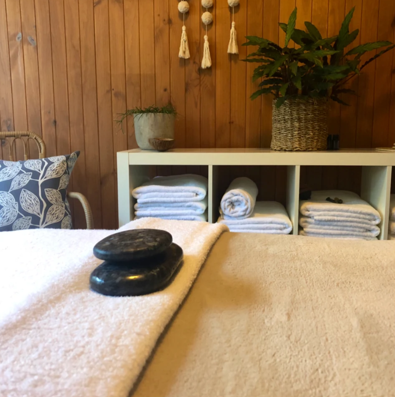 The Massage & Wellbeing Co studio - massage table with hot stones in a relaxing beachy environment